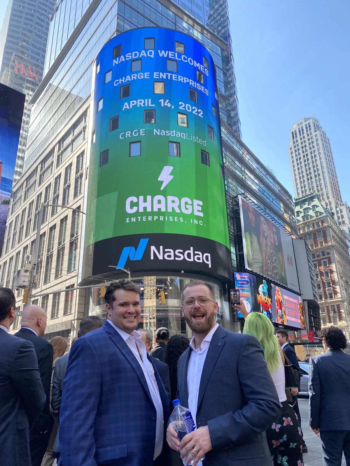 Jon and a colleague in Times Square beneath the Nasdaq tower welcoming Charge Enterprises